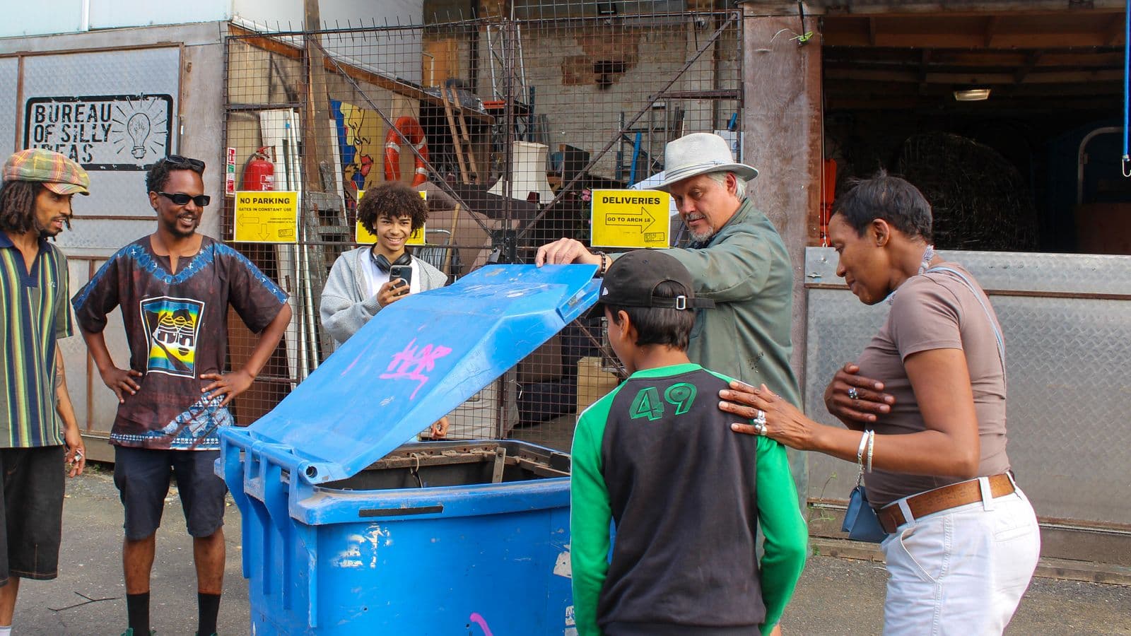A group of people looking into a mechanical wheelie bin