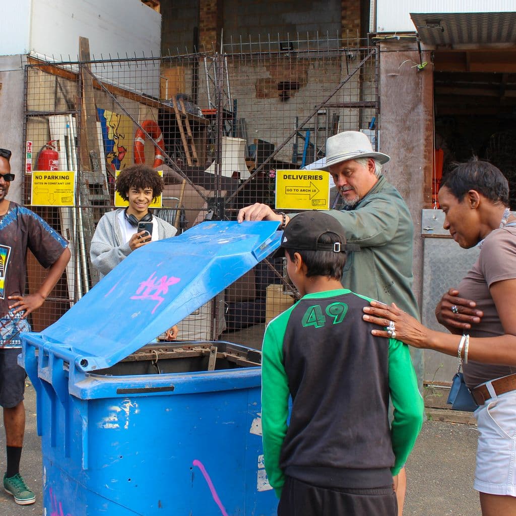 A group of people looking into a mechanical wheelie bin